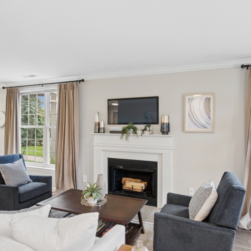 A living room with a fireplace and chairs at The Chapman apartments Rochester MI.