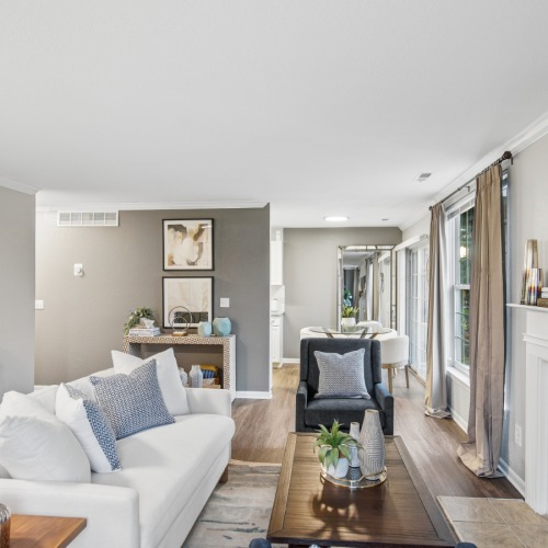 A living room with a large window and a couch at The Chapman Rochester Michigan apartments.